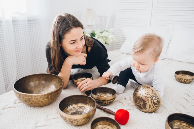 Kleine jongen spelen met Tibetaanse klankschalen zittend op het bed