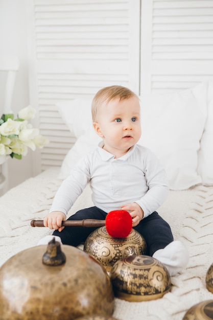 Kleine jongen spelen met Tibetaanse klankschalen zittend op het bed