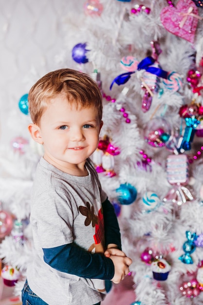 Kleine jongen staat voor een witte kerstboom