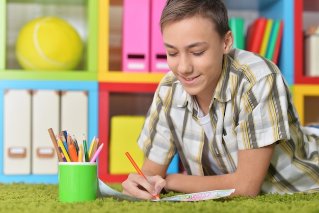 Kleine jongen tekenen terwijl hij op de vloer ligt