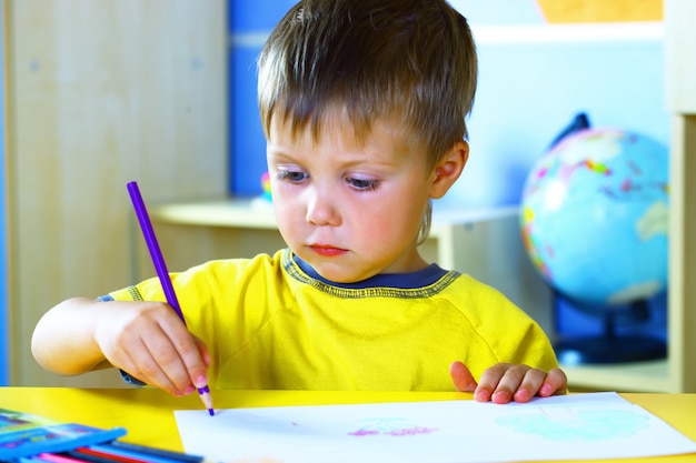 Kleine jongen tekent met gekleurde verf