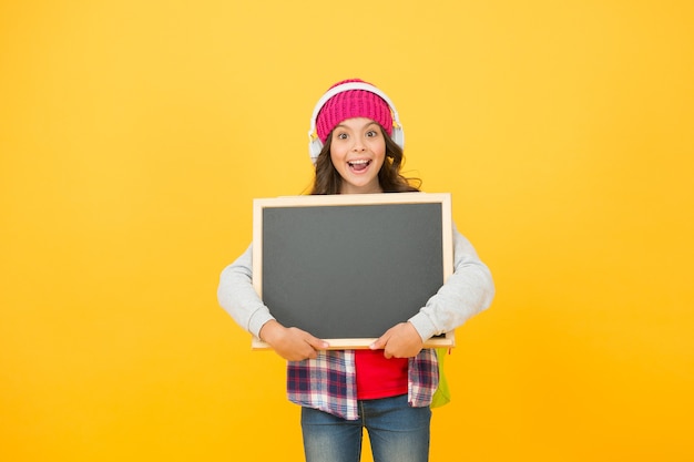 Kleine jongen tiener houdt schoolbord. terug naar school. belangrijke mededeling voor u. zelf onderwijs. gelukkig meisje gele muur, kopieer ruimte. informeren over verkopen. schoolmeisje luister muziek in een koptelefoon.