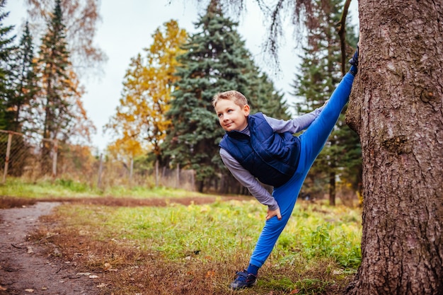 Kleine jongen toont splitst staande bij de boom in het bos