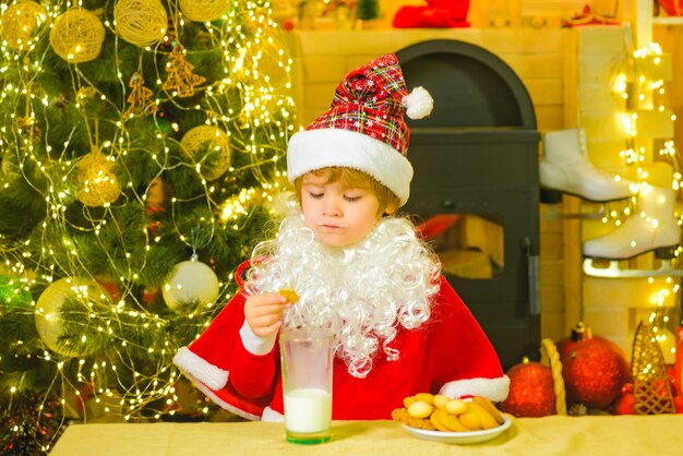 Kleine jongen van de kerstman met baard en snor santa grappig kind dat koekjesportret van kleine s...