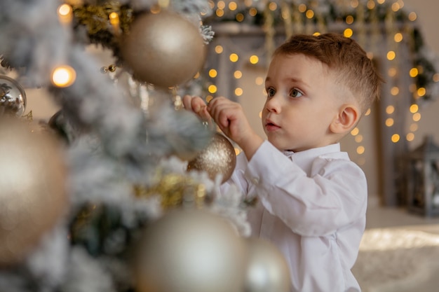 Kleine jongen versiert een kerstboom voor Kerstmis.