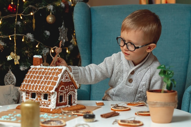 Kleine jongen versiert kerst peperkoek huis