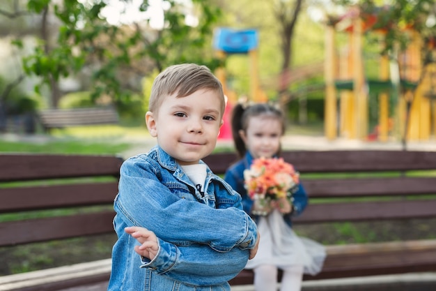 Kleine jongen vormt tegen de achtergrond van een meisje met een boeket bloemen