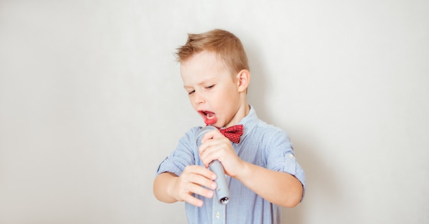 Kleine jongen zingt met microfoon. Muziek, lied en onderwijsconcept