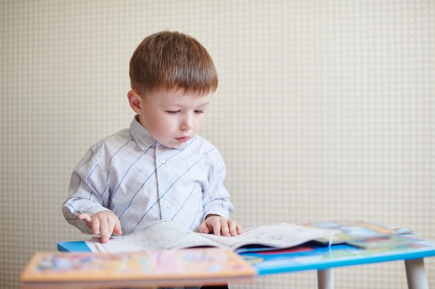 Kleine jongen zit aan de balie en het lezen van een boek