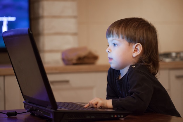 Kleine jongen zit aan de laptop.