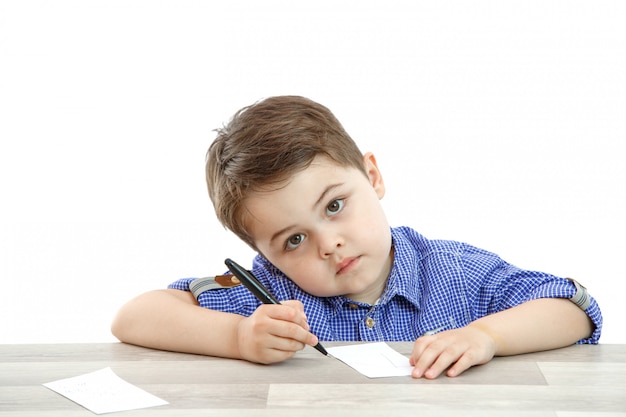 Kleine jongen zit en schrijft schrijft