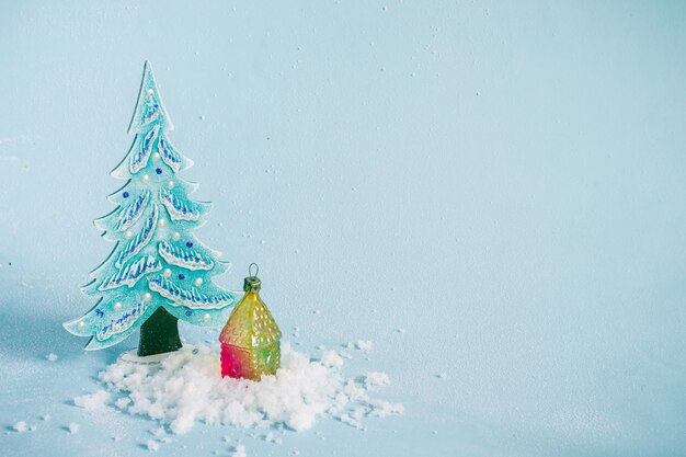 Kleine kerstboom, huis en sneeuw op blauw