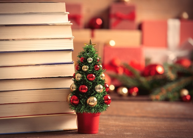 Kleine kerstboom met boeken en geschenkdozen op achtergrond