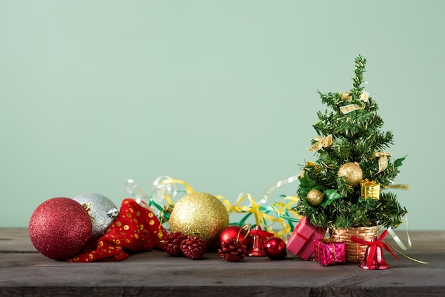 Kleine kerstboom met versieringen op een donkere houten tafel.