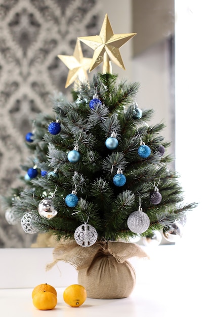 Kleine kerstboom op een witte tafel met mandarijn