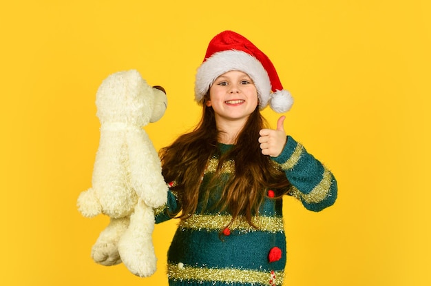 Kleine kerstman met speelgoed klein meisje kerstman hoed rode achtergrond bereiden zich voor op nieuwjaarsfeest kerst favoriete vakantie winter vrolijk seizoen xmas winkelen verkoop