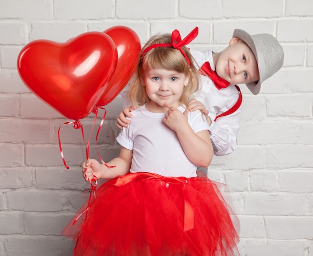 Kleine kinderen houden en oppakken van hart ballonnen. Valentijnsdag en liefde concept, op witte achtergrond