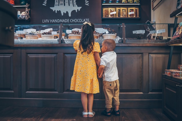 Kleine kinderen kijken naar een vitrine met chocolade snoepjes kiezen