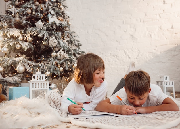 kleine kinderen tekenen op de vloer voor een kerstboom