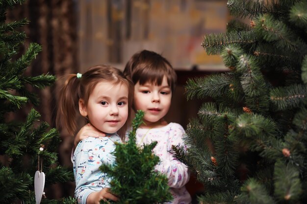 Kleine kinderen verheugen zich over het naderende Nieuwjaar en Kerstmis. Kinderen spelen met plezier rond de kerstboom.