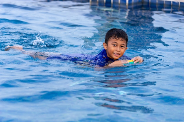 Kleine kinderen zwemmen in het zwembad met behulp van kick-board.