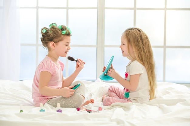 Kleine kindermeisjeszusjes die binnenshuis make-up doen