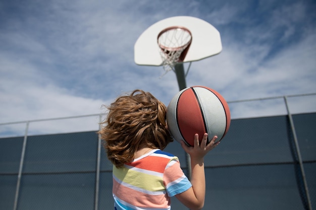 Kleine kindjongen die basketbal speelt met basketbal, basketbal voor kinderen, school