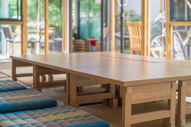 Kleine kleine houten tafels zijn gerangschikt voor lange tafel Japanse kamerstijl op de mat in een glazen kamer die zich voorbereidt op de lunch