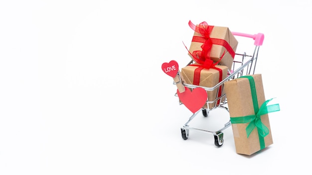 Kleine kruidenierswinkel kar met geschenkdozen op wit oppervlak. Geef geschenken met liefde op Valentijnsdag