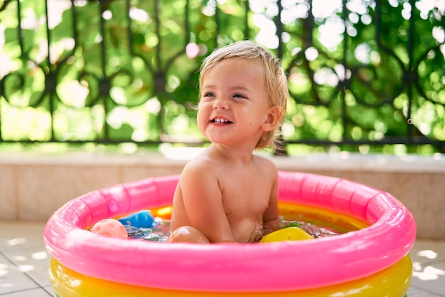 Kleine lachende baby zit in een klein opblaasbaar zwembad