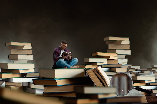 Kleine man leest tussen grote boeken en leerboeken, schaaleffect. Kennis verwerven en onderwijsconcept. Student die het onderwerp bestudeert vóór het examen