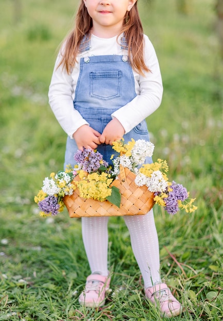 Kleine mandhandtas met gele bloemen en seringen in de handen van een meisje