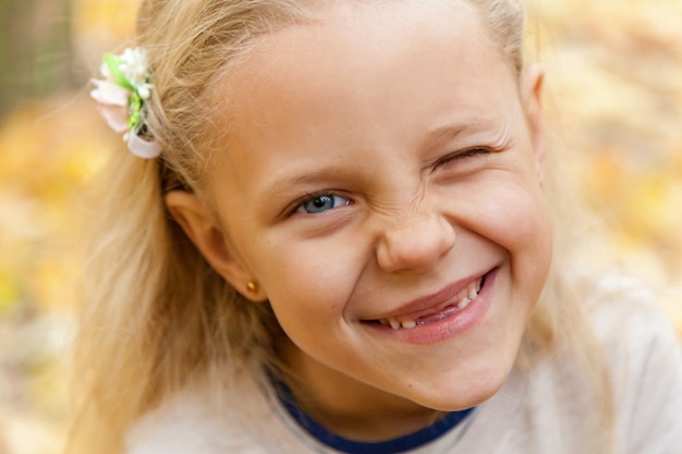 Kleine meid. Het kleine meisje met blauwe ogen en lang blond haar trekt alle gezichten naar de camera.