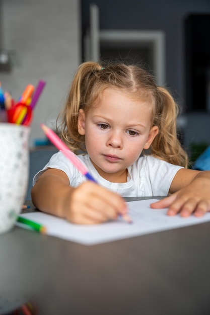 Foto kleine meisje tekent met gekleurde potloden thuis.