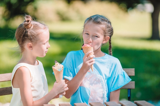 Kleine meisjes die buiten ijs eten in de zomer in het buitencafé