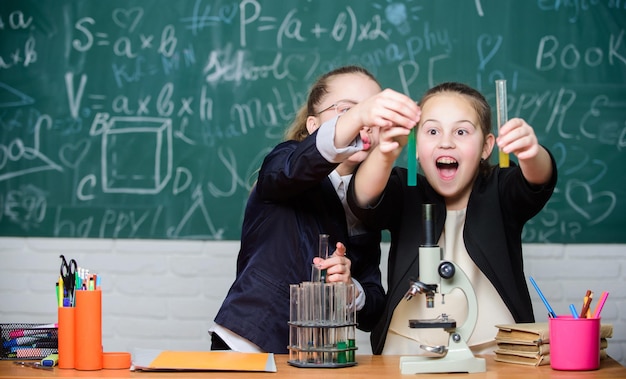 Kleine meisjes in schoollab Scheikundeonderwijs Kleine wetenschapper werkt met microscoop Scheikundeonderzoek Biologieles wetenschapsexperimenten in scheikundelaboratorium Professionele keuze