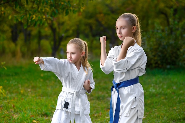 Kleine meisjes in witte kimono tijdens karate trainingsoefeningen in de zomer buiten