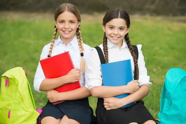 Kleine meisjes met boeken en rugzakken kinderen houden notitieboekje voor het maken van aantekeningen gelukkige jeugd terug naar school tiener leerlingen klaar voor les voorbereiden op examen samen studeren buiten