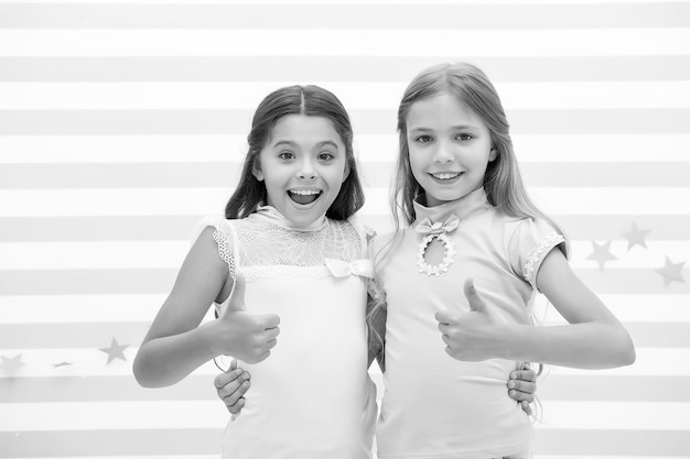 Kleine meisjes van hoge kwaliteit tonen duimen als symbool van succes van hoge kwaliteit Kleine meisjes zijn beste vrienden