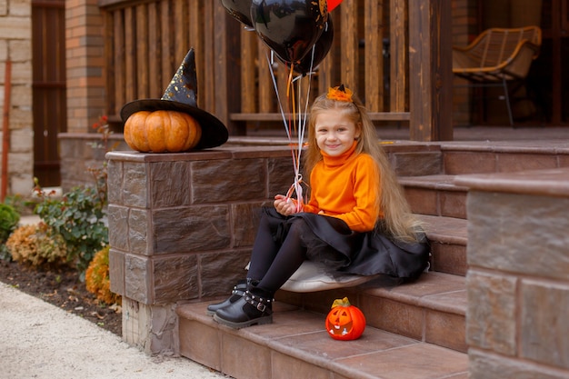 kleine meisjes voor de deur van het huis in een Halloween-kostuum