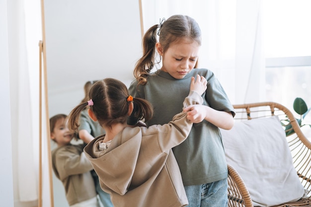 Kleine meisjeszusjes hebben ruzie bij de spiegel in de kinderkamer thuis