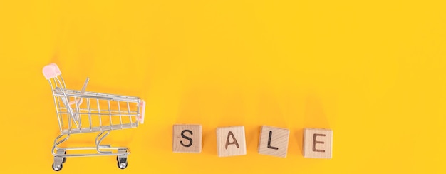 Foto kleine metalen kar en woord verkoop op gele achtergrond shopping concept