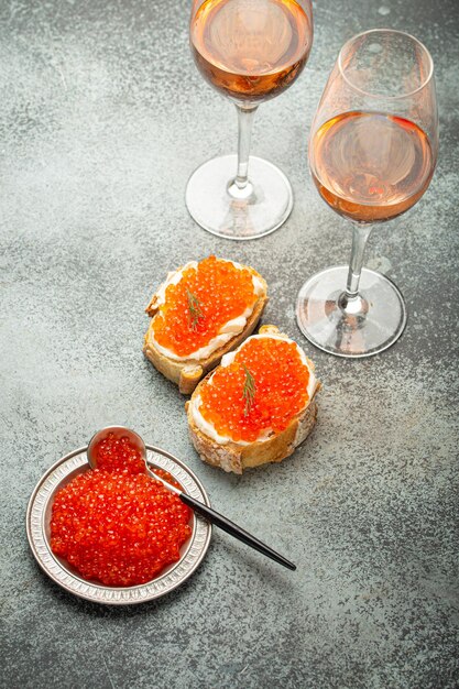 Foto kleine metalen plaat met rode zalmkaviaar twee kaviaar toastjes.