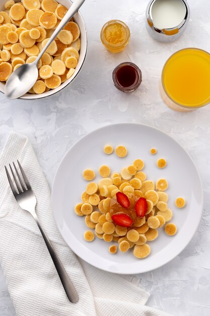 Kleine mini-pannenkoekgranen. Huisgemaakt ontbijt met frambozen, jam en sap op grijze achtergrond