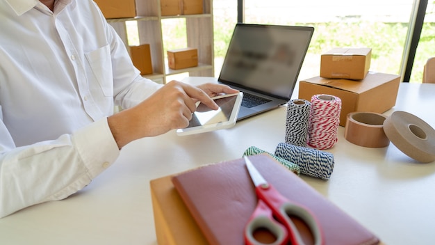 kleine ondernemer MKB, jonge Aziatische man aan het werk met laptop en levering verpakking