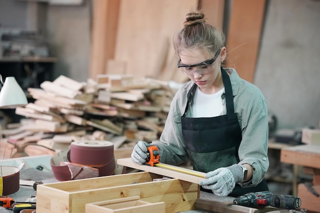 Foto kleine onderneming van een jonge vrouw aantrekkelijke jonge vrouw timmerman ontwerper werkt in werkplaats