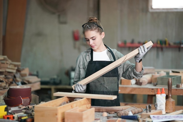 Kleine onderneming van een jonge vrouw Aantrekkelijke jonge vrouw timmerman ontwerper werkt in werkplaats