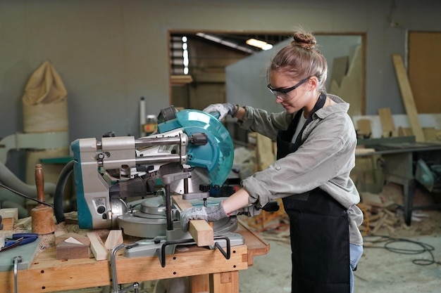 Kleine onderneming van een jonge vrouw Mooie jonge vrouwelijke werknemer in een meubelwerkkamer die hout meet