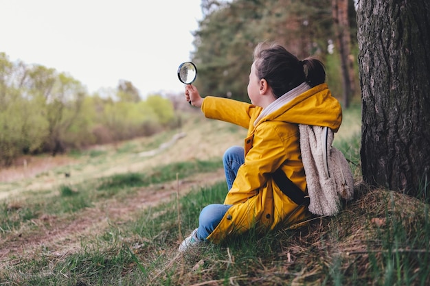 Foto kleine ontdekkingsreiziger met vergrootglas speelt in het bos zoeken en onderzoeken