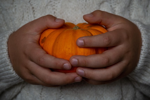 kleine oranje pompoen in de handen van een kind